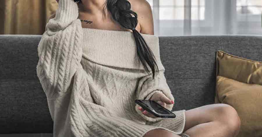 A photo of a woman on a couch holding a phone