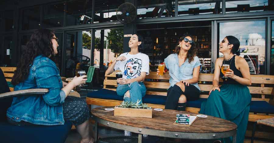 single foreign ladies sitting on a bench with drinks